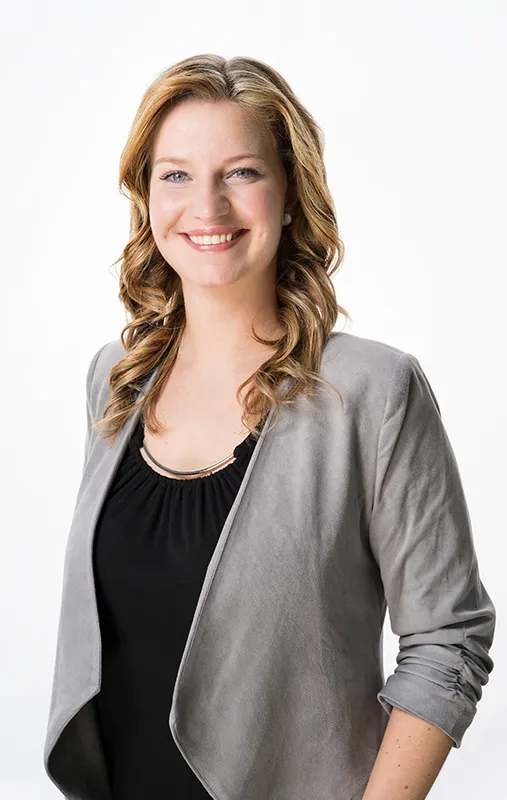 Studioporträt einer Frau im grauen Blazer vor weißem Hintergrund